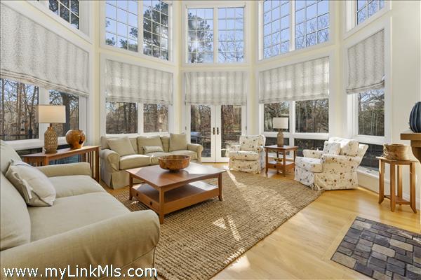 The living room with two-stories of windows, gas fireplace and access to the back deck and pool.