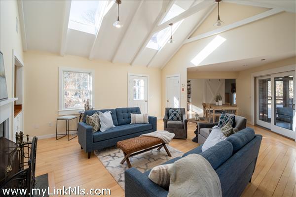 Warm bright newly renovated  living room with wet bar, refinished hardwood floors, cathedral w/ skylights