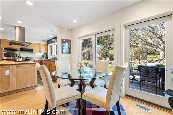 Breakfast nook located between kitchen and den, with slider to rear deck viewed from entrance to rear staircase to second floor