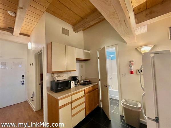 kitchen with post and beam ceiling opens to full bath