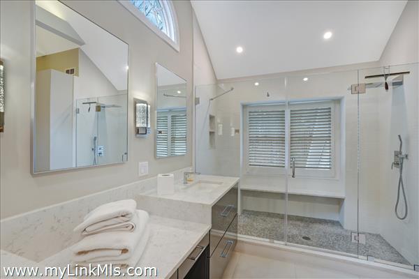 Oversized tile shower has a glass enclosure.