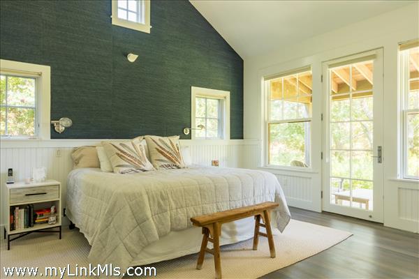 Primary bedroom with doors out to a private deck overlooking the pond