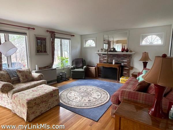 Large front windows in sunny living room w/ Palladian side windows and hardwood floors