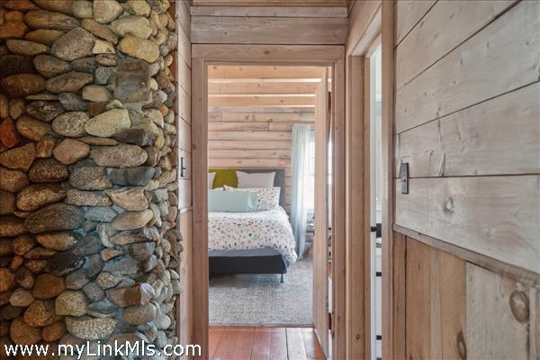 Coastal charm throughout - beach stone chimney looking toward primary bedroom
