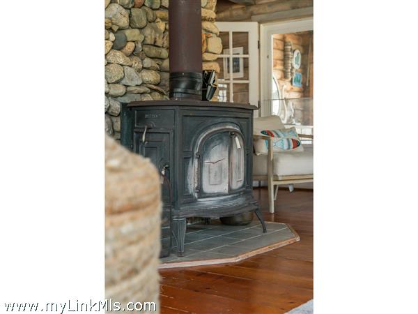 Wood stove accents the beach stone fireplace and provides warmth on chilly evenings