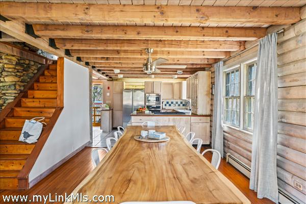 open floor plan with beautiful spaces and materials, wood beams and accent walls, open staircase leads to the second floor bedrooms