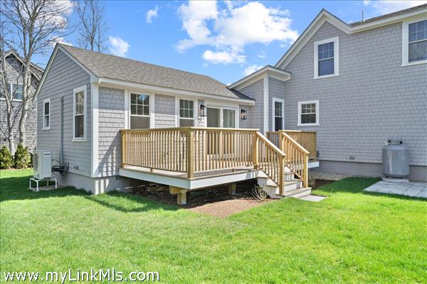 Spacious outdoor living atop the first floor deck off the accessory dwelling unit. Adjacent patio and lush green yard.