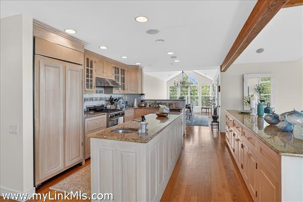 Gourmet kitchen with exposed wood beams, flowing to the breakfast nook