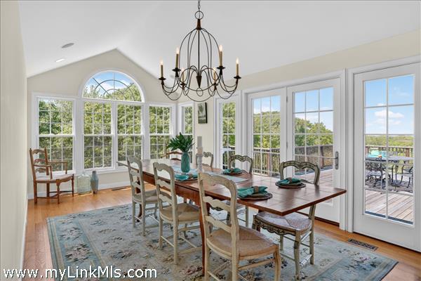 The dramatic arched windows and a classic statement chandelier, this bright and airy room offers panoramic views of the surrounding landscape and opens directly onto the expansive back deck, creating a flawless indoor-outdoor flow for entertaining