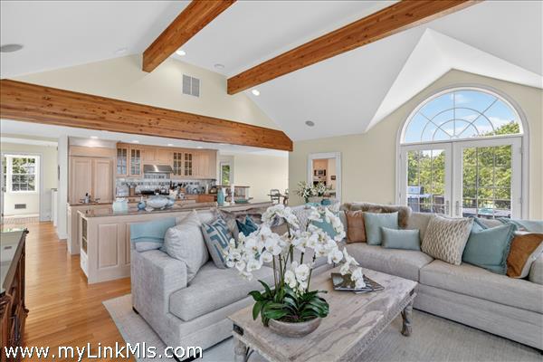 Spacious and airy living room showcasing gorgeous post-and-beam details, a central fireplace, and beautiful hardwood floors