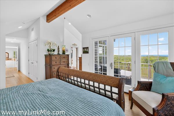Primary bedroom featuring vaulted ceilings, exposed beams, and private deck access