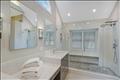 Oversized tile shower has a glass enclosure.