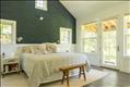 Primary bedroom with doors out to a private deck overlooking the pond
