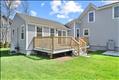 Spacious outdoor living atop the first floor deck off the accessory dwelling unit. Adjacent patio and lush green yard.
