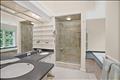The spacious primary bathroom serves as a serene retreat, featuring a double vanity, a large glass-enclosed shower, a deep soaking tub, and custom floor-to-ceiling built-in shelving for linen and decor storage