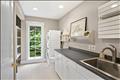 Bright and spacious laundry room featuring a long expanse of counter space, extensive cabinetry for organization, a dedicated utility sink, and a stacked washer and dryer setup