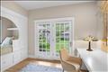 A bright and captivating bedroom featuring a custom arched built-in bed alcove with integrated under-bed storage drawers, a seamless built-in desk workstation, and double glass doors that open directly to the outside