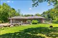 The scenic side yard is beautifully terraced with classic New England stone walls, creating a manicured backdrop that seamlessly blends with the natural woodland surroundings