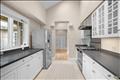 The bright, gallery-style kitchen features sleek countertops, premium stainless steel appliances, and impressive vaulted ceilings with a skylight that floods the space with natural light