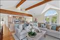 Spacious and airy living room showcasing gorgeous post-and-beam details, a central fireplace, and beautiful hardwood floors