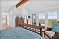 Primary bedroom featuring vaulted ceilings, exposed beams, and private deck access